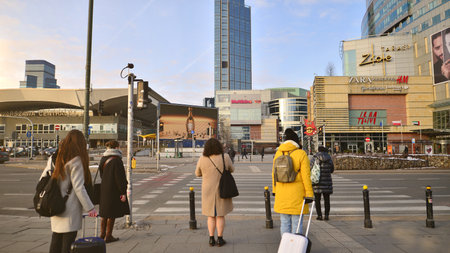 Warsaw, Poland. 10 February 2023. People of different ages crossing the road through. View of a city street with residents, tourists and modern buildings.のeditorial素材