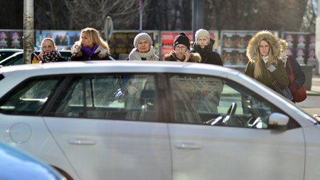 Warsaw, Poland. 8 March 2023. Crowd of people walking down an urban sidewalk with bright glowing...