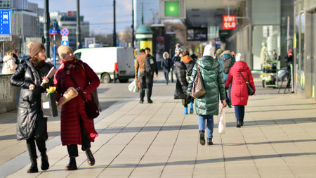 Warsaw, Poland. 8 March 2023. Crowd of people walking down an urban sidewalk with bright glowing sunlight in the background on a busy street in downtown.のeditorial素材