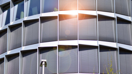Abstract fragment of contemporary architecture, walls made of glass and concrete. Abstract closeup of the glass-clad facade of a modern building covered in reflective plate glass.の写真素材