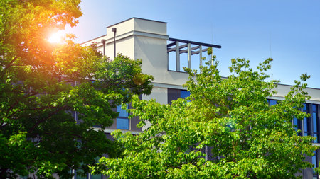 eco architecture. Details of facade glass and aluminum panels on building. Green tree and modern...