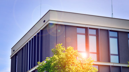 eco architecture. Details of facade glass and aluminum panels on building. Green tree and modern...