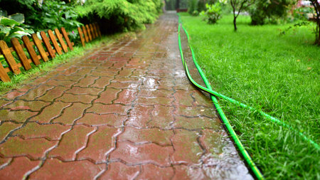 Drops of heavy rain on sidewalk surface. Rain water on the surface of the flood the sidewalk in garden.の写真素材