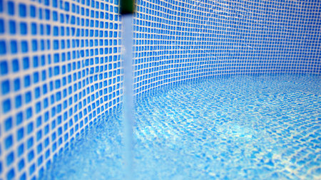 Water flowing from the hose into the pool filling. The inside of the swimming pool.の写真素材