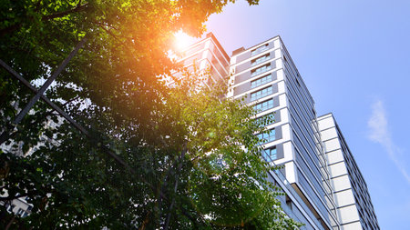 Modern residential building with new apartments in a green residential area. Eco architecture. Green tree and new apartment building. The harmony of nature and modernity.の写真素材