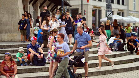 Warsaw, Poland. July 29, 2023. Crowd of people walking on a street. A crowd moving against a background of an urban old city landscape.のeditorial素材