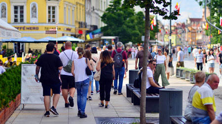 Warsaw, Poland. July 29, 2023. Crowd of people walking on a street. A crowd moving against a background of an urban old city landscape.のeditorial素材