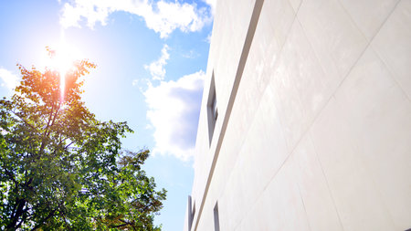 Modern white concrete building walls against blue sky. eco architecture. Green trees and concrete office building. The harmony of nature and modernity.の写真素材