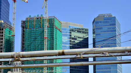 Modern high-rise buildings under construction next to glass skyscrapers in background.の写真素材