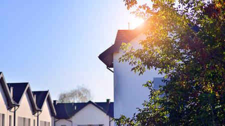Suburban neighborhood with condominium complex. Suburban area with modern geometric family houses. Row of family houses against blue sky.の写真素材