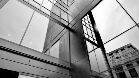 A view at a straight facade of a modern building with a dark gray facade. Dark gray metallic panel...