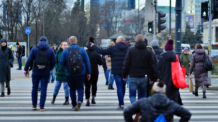 Warsaw, Poland. 29 December 2023. Crowd of people crossing street on traffic light zebra in the city at rush hour. Lifestyle in a big city in Europe.のeditorial素材