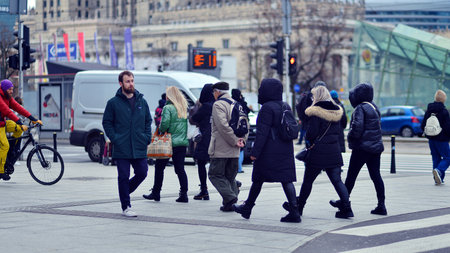 Warsaw, Poland. 29 December 2023. Crowd of people crossing street on traffic light zebra in the city at rush hour. Lifestyle in a big city in Europe.のeditorial素材