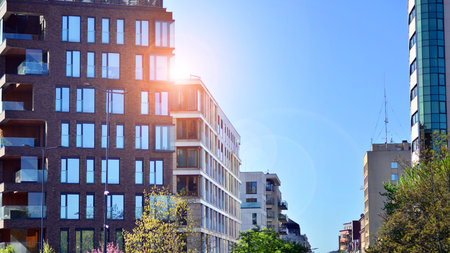 Eco architecture. Green tree and new residential building. Harmony of nature and modernity. Modern apartment building with new apartments in a green residential area.の写真素材