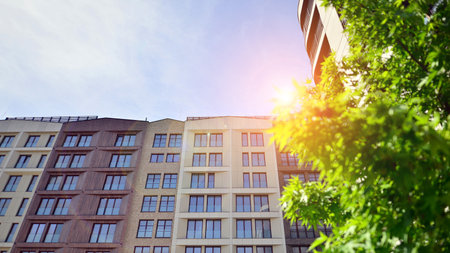 Modern residential building with new apartments in a green residential area. Eco architecture. Green tree and new apartment building. The harmony of nature and modernity.の写真素材