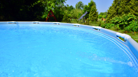 Swimming pool with metal frame for home and garden. Frame swimming pool in the yard. Garden in the...