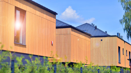 Residential homes with modern wood facade. Terraced family homes in newly developed housing estate....