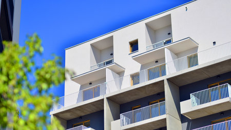 New modern block of flats in green area. Eco apartment building saving energy and fresh air concept. Green tree and new apartment building. The harmony of nature and modernity.の写真素材