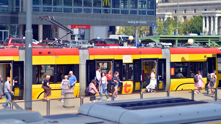 Warsaw, Poland. 17 August 2024. Urban transportation infrastructure and urban landscape. Yellow tram at street. City traffic.のeditorial素材