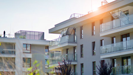 A apartment building with a lot of balconies and windows. The building is surrounded by trees and has a lot of greenery. Green surroundings of buildings. Ecological housing estate.の写真素材
