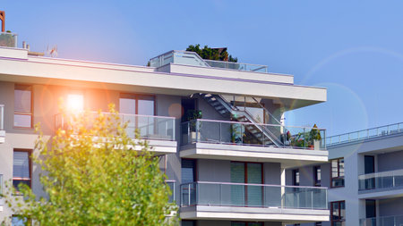 A apartment building with a lot of balconies and windows. The building is surrounded by trees and has a lot of greenery. Green surroundings of buildings. Ecological housing estate.の写真素材