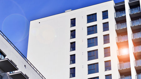 Modern high-rise apartment building in white, stand tall against a blue sky, exemplifying innovative...