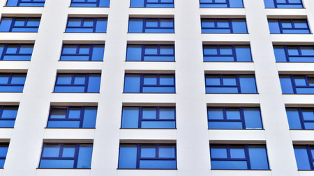 Modern high-rise apartment building in white, stand tall against a blue sky, exemplifying innovative...