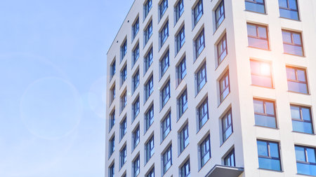 Modern high-rise apartment building in white, stand tall against a blue sky, exemplifying innovative...