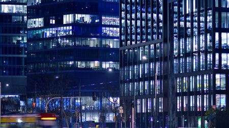 Office building in the evening with lightened workspaces. Modern, glazed skyscraper in financial district. Late hours in the office.の写真素材