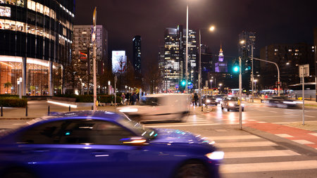 Warsaw, Poland. 21 November 2024. Street photography of cars on the street at night. The light trails on the modern building background.のeditorial素材