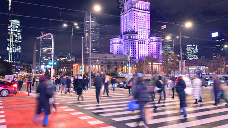 Warsaw, Poland. 22 November 2024. Street of a big city. People of different ages crossing the road through. View of a city street with residents, tourists and modern buildings.のeditorial素材