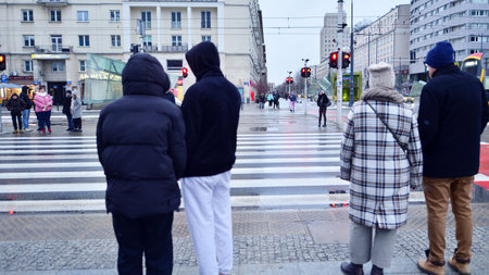 Warsaw, Poland. 12 January 2025. People of different ages crossing the road through. Winter street...