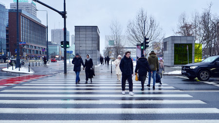 Warsaw, Poland. 12 January 2025. People of different ages crossing the road through. Winter street...