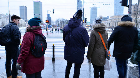 Warsaw, Poland. 12 January 2025. People of different ages crossing the road through. Winter street of a big city. View of a city street with residents, tourists and modern buildingのeditorial素材