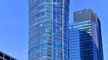 Glass building with transparent facade of the building and blue sky. Structural glass wall reflecting blue sky. Abstract modern architecture fragment. Contemporary architecturalの写真素材