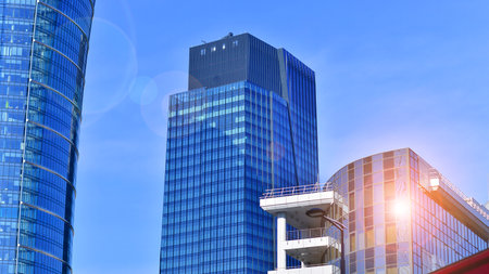 Glass building with transparent facade of the building and blue sky. Structural glass wall reflecting blue sky. Abstract modern architecture fragment. Contemporary architecturalの写真素材