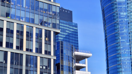 Glass building with transparent facade of the building and blue sky. Structural glass wall reflecting blue sky. Abstract modern architecture fragment. Contemporary architecturalの写真素材