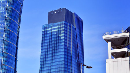Glass building with transparent facade of the building and blue sky. Structural glass wall reflecting blue sky. Abstract modern architecture fragment. Contemporary architecturalの写真素材