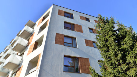 Apartment building with symmetrical modern architecture in the city. Modern apartment building on a sunny day. Facade of a modern apartment building. Bottom view.の写真素材