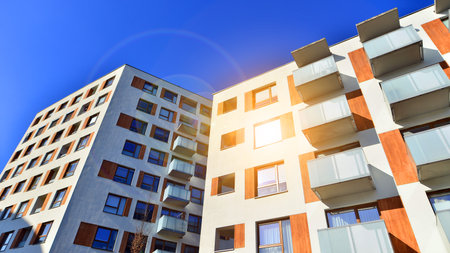 Apartment building with symmetrical modern architecture in the city. Modern apartment building on a sunny day. Facade of a modern apartment building. Bottom view.の写真素材