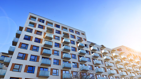 Apartment building with symmetrical modern architecture in the city. Modern apartment building on a sunny day. Facade of a modern apartment building. Bottom view.の写真素材
