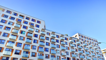 Apartment building with symmetrical modern architecture in the city. Modern apartment building on a sunny day. Facade of a modern apartment building. Bottom view.の写真素材