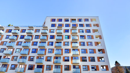 Apartment building with symmetrical modern architecture in the city. Modern apartment building on a sunny day. Facade of a modern apartment building. Bottom view.の写真素材