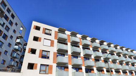 Apartment building with symmetrical modern architecture in the city. Modern apartment building on a sunny day. Facade of a modern apartment building. Bottom view.の写真素材