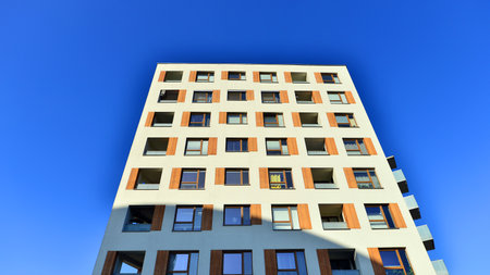 Apartment building with symmetrical modern architecture in the city. Modern apartment building on a sunny day. Facade of a modern apartment building. Bottom view.の写真素材