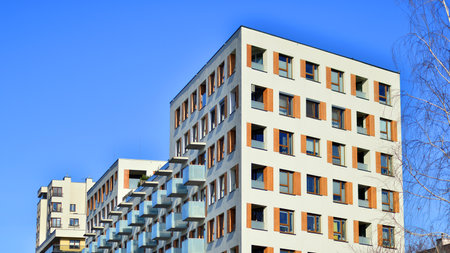 Apartment building with symmetrical modern architecture in the city. Modern apartment building on a sunny day. Facade of a modern apartment building. Bottom view.の写真素材