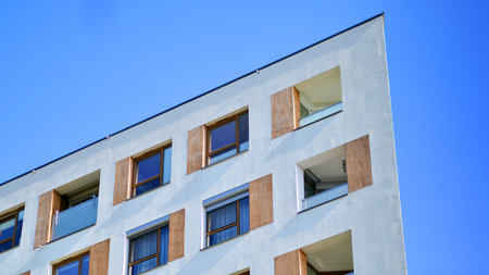 Apartment building with symmetrical modern architecture in the city. Modern apartment building on a sunny day. Facade of a modern apartment building. Bottom view.の写真素材