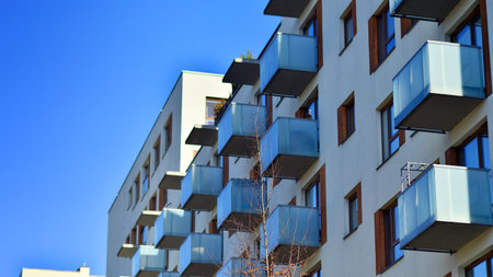 Apartment building with symmetrical modern architecture in the city. Modern apartment building on a sunny day. Facade of a modern apartment building. Bottom view.の写真素材