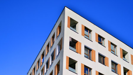Apartment building with symmetrical modern architecture in the city. Modern apartment building on a sunny day. Facade of a modern apartment building. Bottom view.の写真素材