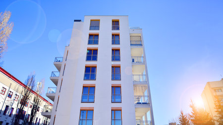 Apartment building with symmetrical modern architecture in the city. Modern apartment building on a sunny day. Facade of a modern apartment building. Bottom view.の写真素材